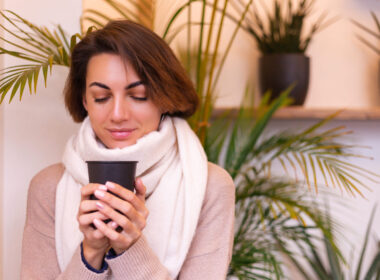 a girl in a cozy cafe warms herself up with a cup of hot coffee