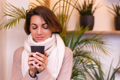 a girl in a cozy cafe warms herself up with a cup of hot coffee