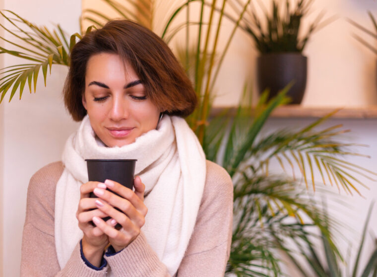 a girl in a cozy cafe warms herself up with a cup of hot coffee