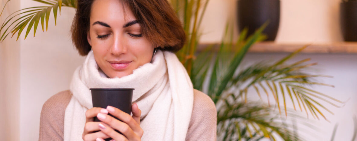 a girl in a cozy cafe warms herself up with a cup of hot coffee